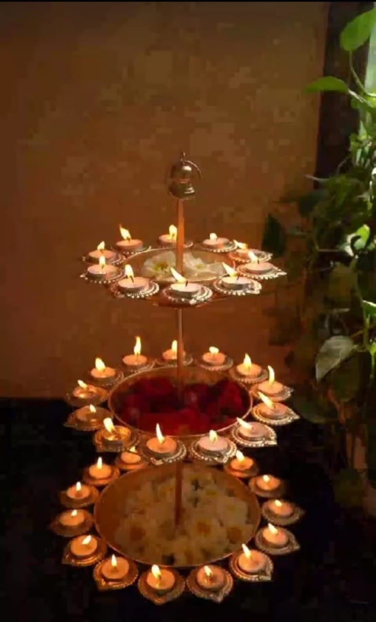 three-tiered golden metal Urli bowl with a lotus design